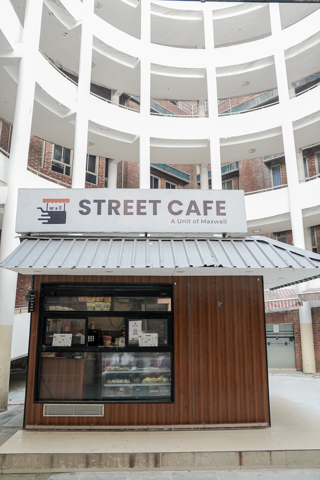 The Street Cafe kiosk, a unit of Maxwell, in a courtyard beneath curved white balconies